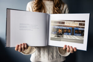 Documentaire straatfotografie van mensen op een bankje terwijl het stadsleven voorbijrijdt – beeld uit het fotoboek ‘Tijd die niet terugkeert, verhalen uit het alledaagse’ van documentaire fotograaf Martine Goulmy.