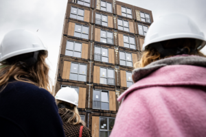 Zakelijke bouwfotografie op een nieuwbouwproject, met professionals in veiligheidshelmen die de voortgang van de bouw bekijken.